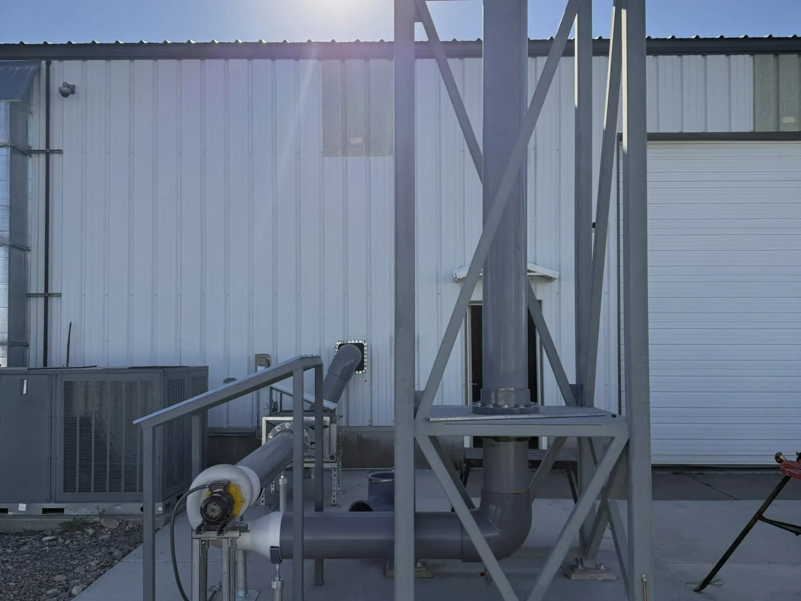 Laboratory exhaust stack and its ductwork beside the white steel Raven-Flint headquarters building in Idaho Falls