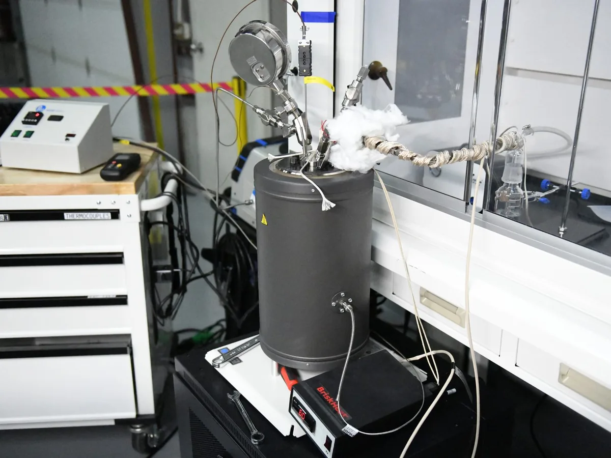 An insulated bench vessel with wrapped lines on a bench inside a fume hood