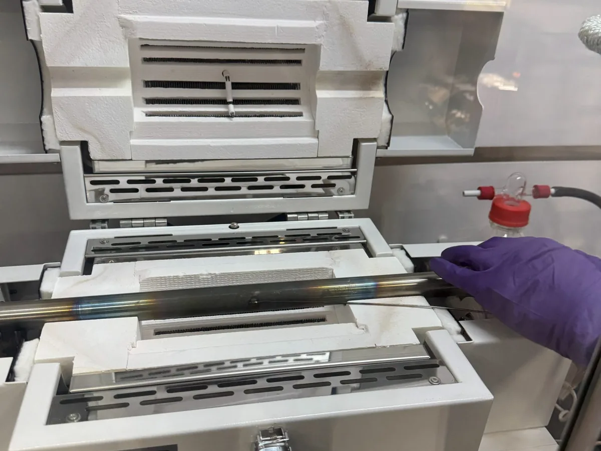 A split tube furnace open on the bench with the work tube in place