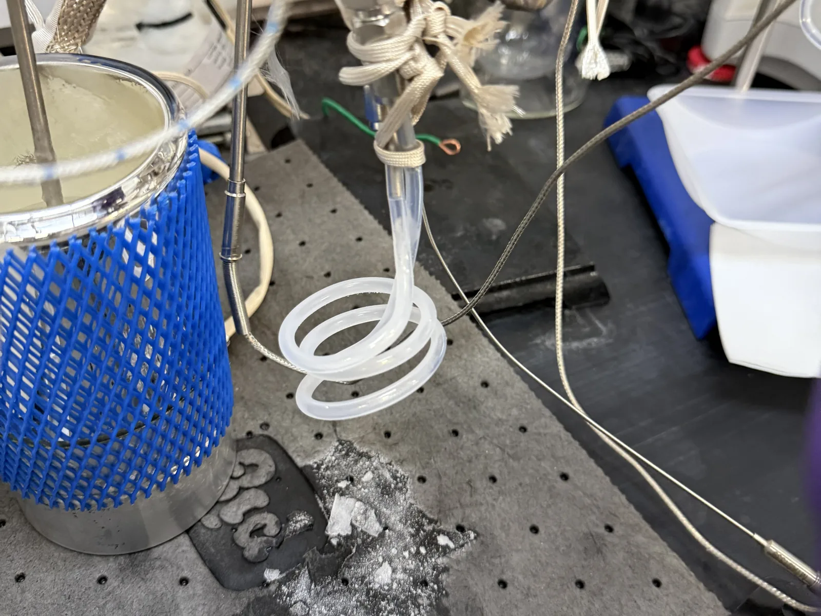 Clear coiled line with white solid uranium hexafluoride inside, beside a blue-jacketed cold trap, white crystals on the laboratory bench