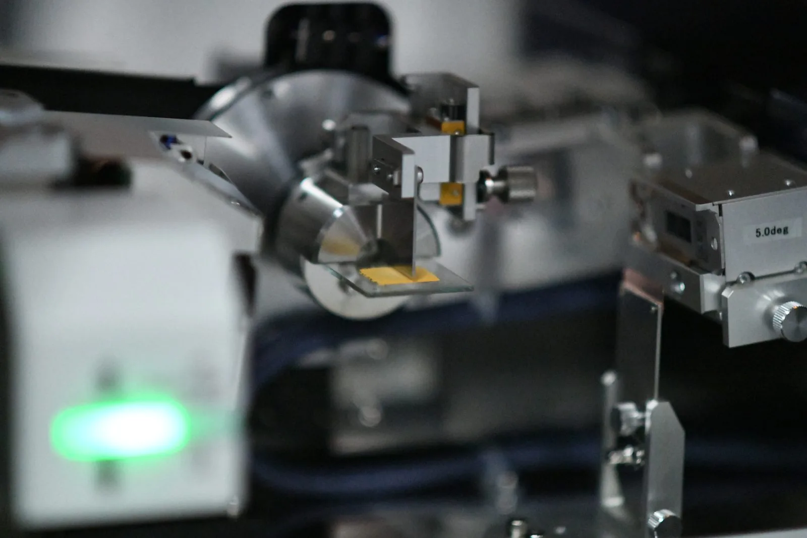 Close view of an X-ray diffractometer sample stage with a prepared slide in place and a green indicator lit